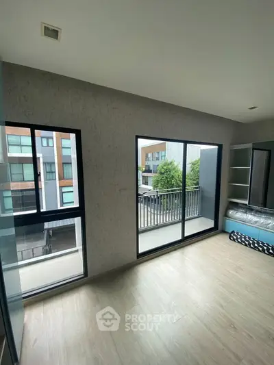 Modern bedroom with large windows and balcony access in urban apartment