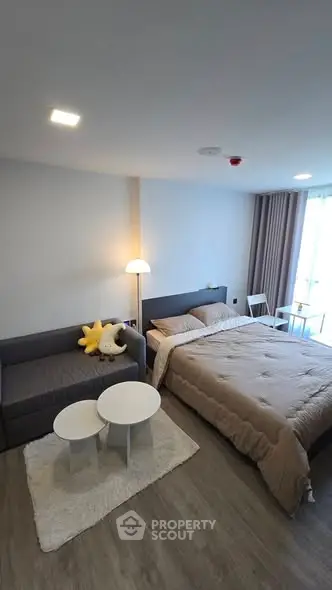 Cozy bedroom with modern decor and natural light, featuring a comfortable bed and stylish seating area.