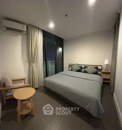 Cozy and well-lit bedroom with a large comfortable bed, wooden flooring, and access to a private balcony offering a serene retreat in a modern apartment.