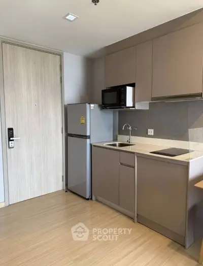 Modern compact kitchen with sleek cabinetry and integrated appliances in a stylish apartment.