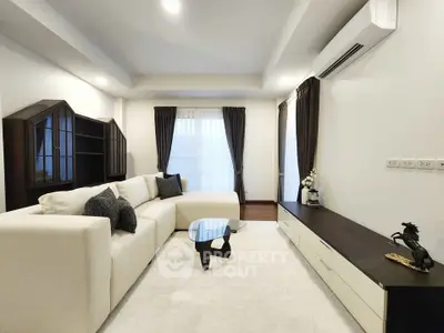 Modern living room with elegant furniture and stylish decor, featuring a cozy white sofa and sleek air conditioning unit.