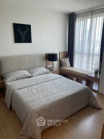 Modern bedroom with stylish decor and large window offering natural light.