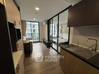 Modern apartment interior with open layout, featuring sleek kitchen and spacious living area with large windows.