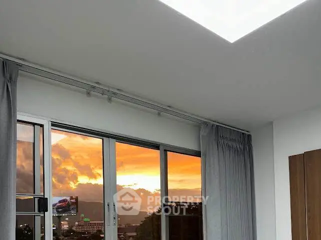 Modern apartment with stunning sunset view through large windows and elegant curtains.