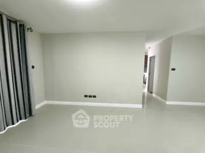 Spacious unfurnished living room with modern tile flooring and neutral walls, ready for customization.