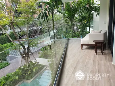 Luxurious balcony with lush garden view and modern glass railing in upscale property.