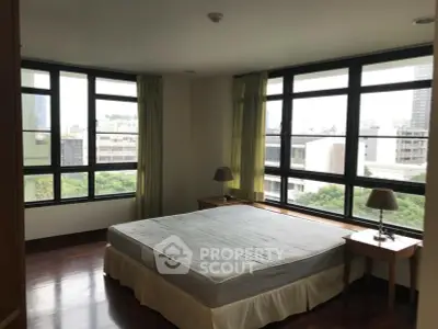 Spacious bedroom with large windows offering city views and natural light.
