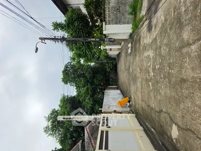 Charming residential street view with lush greenery and secure gated entrance.