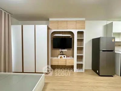 Modern studio apartment with sleek built-in storage and contemporary kitchen appliances.