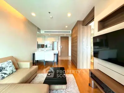 Modern living room with sleek design, featuring a cozy beige sofa, glass coffee table, and open kitchen layout.