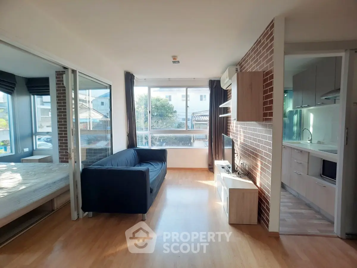 Modern apartment living room with open kitchen and large windows for natural light.