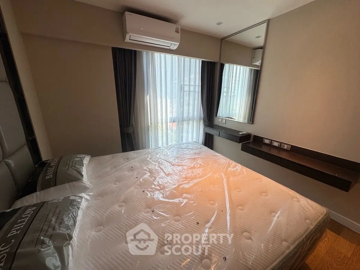 Modern bedroom with large window and air conditioning, featuring a comfortable bed and stylish decor.