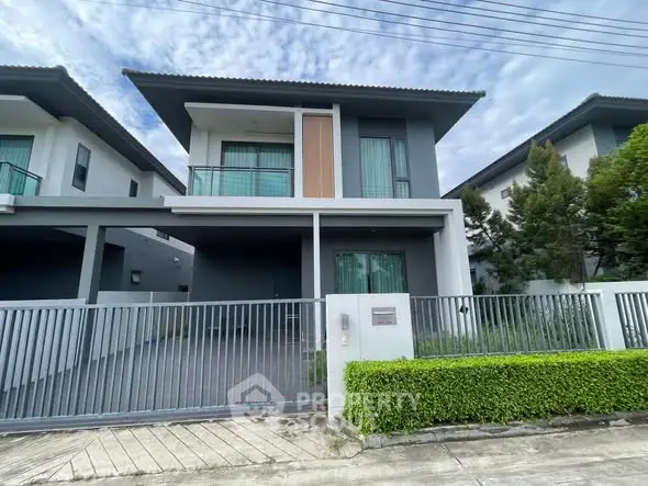Modern two-story house with sleek design and gated entrance in a serene neighborhood.