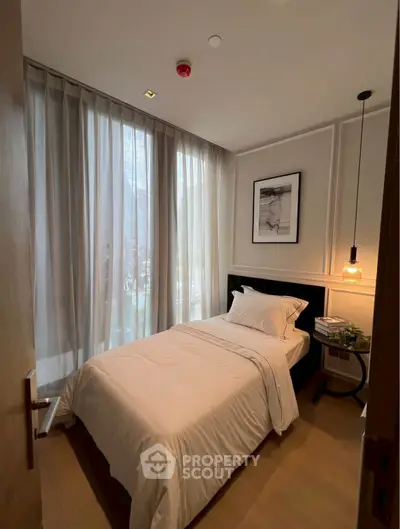 Cozy bedroom with single bed, elegant lighting, and floor-to-ceiling curtains.