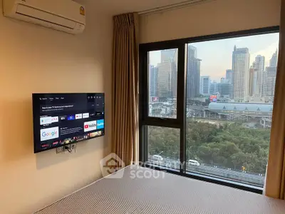 Modern bedroom with city view, wall-mounted TV, and air conditioning in urban apartment.