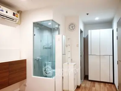 Modern apartment interior with glass-enclosed bathroom and sleek storage solutions.