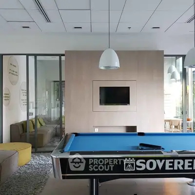Modern recreation room with pool table and cozy seating area in a stylish apartment complex.