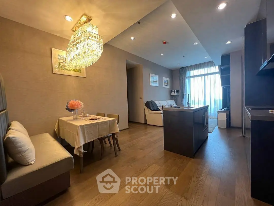 Luxurious open-plan living room with elegant chandelier and modern kitchen island.