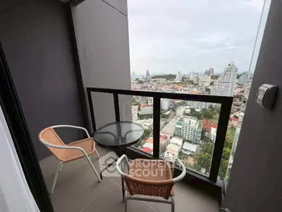 Stunning city view from a modern high-rise balcony with cozy seating area.