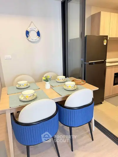 Modern kitchen with dining area featuring stylish blue chairs and sleek appliances.
