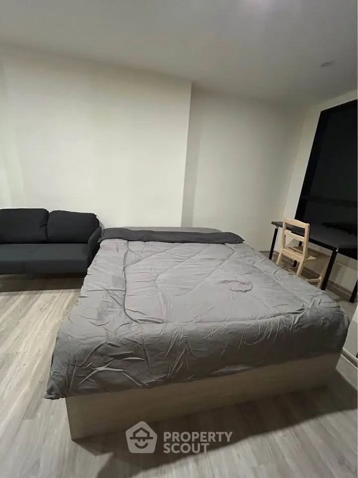 Modern bedroom with cozy bed, sleek sofa, and minimalist desk setup.