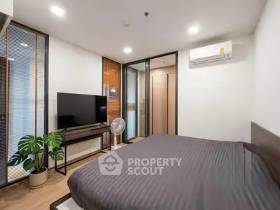 Modern bedroom with sleek design, featuring a large TV, air conditioning, and stylish decor.