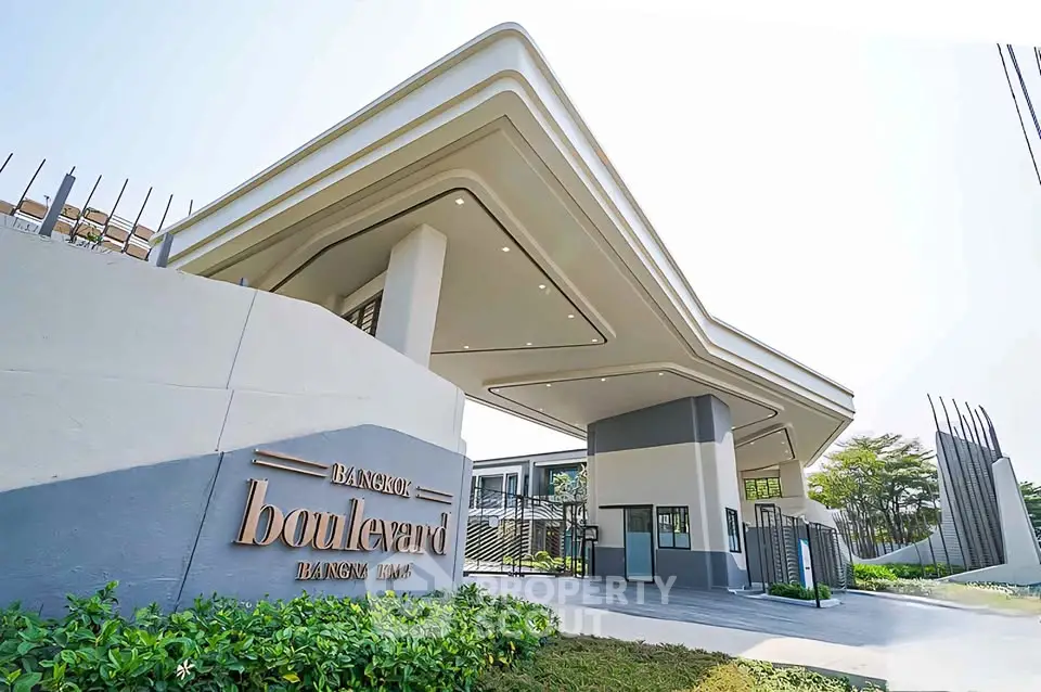 Modern entrance of Bangkok Boulevard with sleek architectural design and lush greenery.