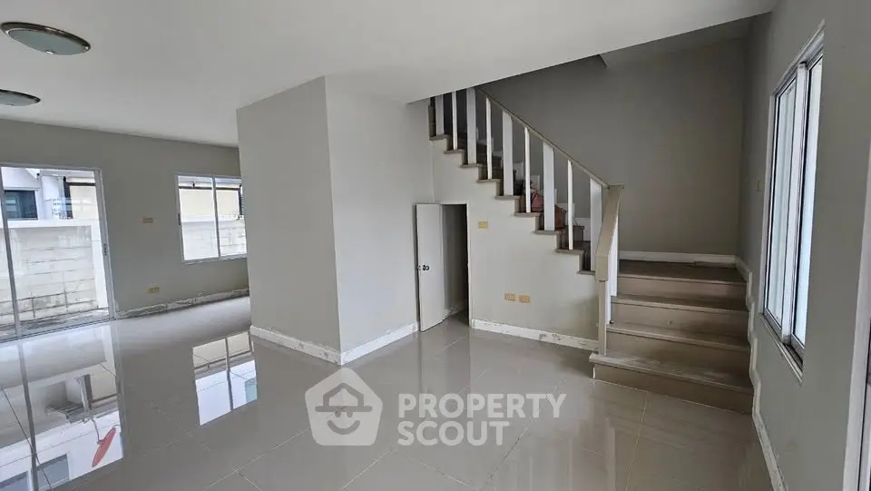 Spacious modern living room with staircase and large windows, perfect for family gatherings.