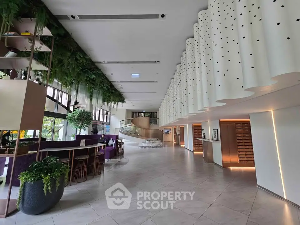 Luxurious modern lobby with unique ceiling design and lush greenery, perfect for upscale living.