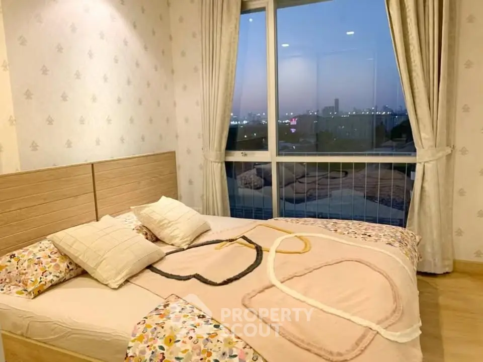 Cozy bedroom with large window offering stunning city view at dusk