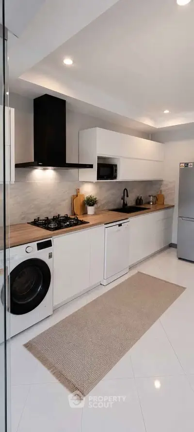 Modern kitchen with sleek white cabinets, gas stove, and integrated appliances in a stylish open layout.
