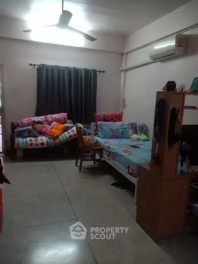Cozy bedroom with twin beds, colorful bedding, and air conditioning.