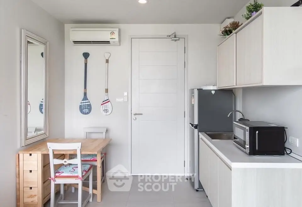 Modern kitchen with sleek cabinetry and compact dining area, featuring a microwave and fridge.