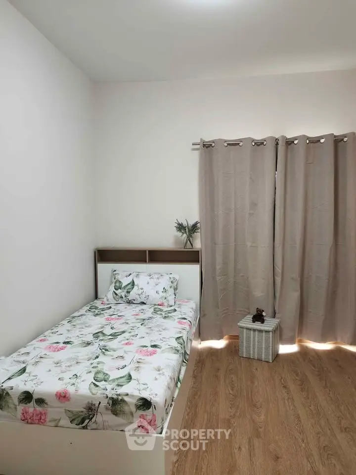 Cozy bedroom with floral bedding and wooden flooring, perfect for a peaceful retreat.
