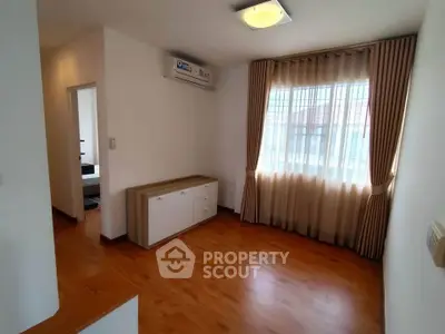 Bright living room with wooden flooring and large window, perfect for cozy gatherings.