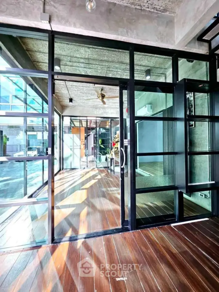Modern industrial-style entrance with glass walls and wooden flooring, perfect for urban living.