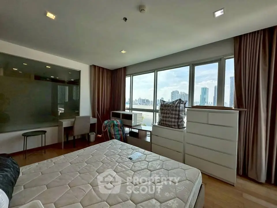 Spacious bedroom with city view, large windows, and modern furnishings in a high-rise apartment.