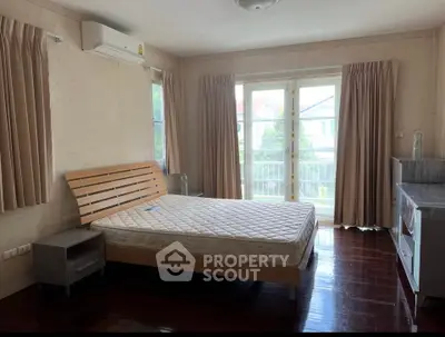 Spacious bedroom with large windows and wooden flooring in a modern home.