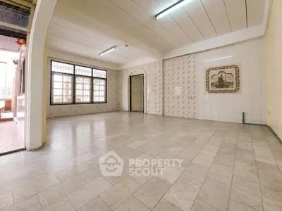 Spacious empty room with tiled flooring and large windows, ideal for customization.