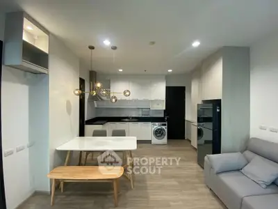 Modern open-plan living room with kitchen, featuring sleek furniture and built-in appliances.