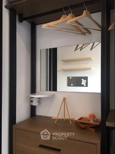 Modern closet with mirror and wooden hangers in stylish interior design.