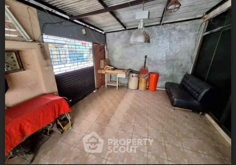 Spacious tiled room with industrial vibe, featuring a black sofa and metal ceiling, ideal for creative use.