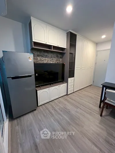 Modern living room with sleek cabinetry and stainless steel fridge, perfect for stylish urban living.