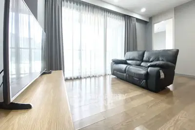 Spacious living room with modern leather sofa and large window for natural light.