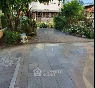 Charming garden view with paved pathway and lush greenery, perfect for outdoor relaxation.
