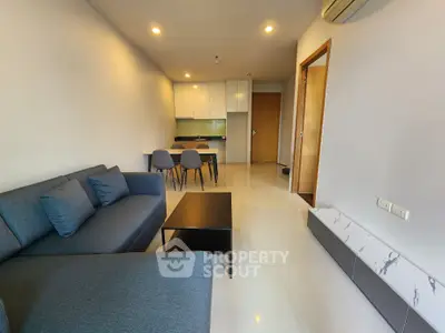 Modern living room with sleek furniture and open kitchen layout in a stylish apartment.