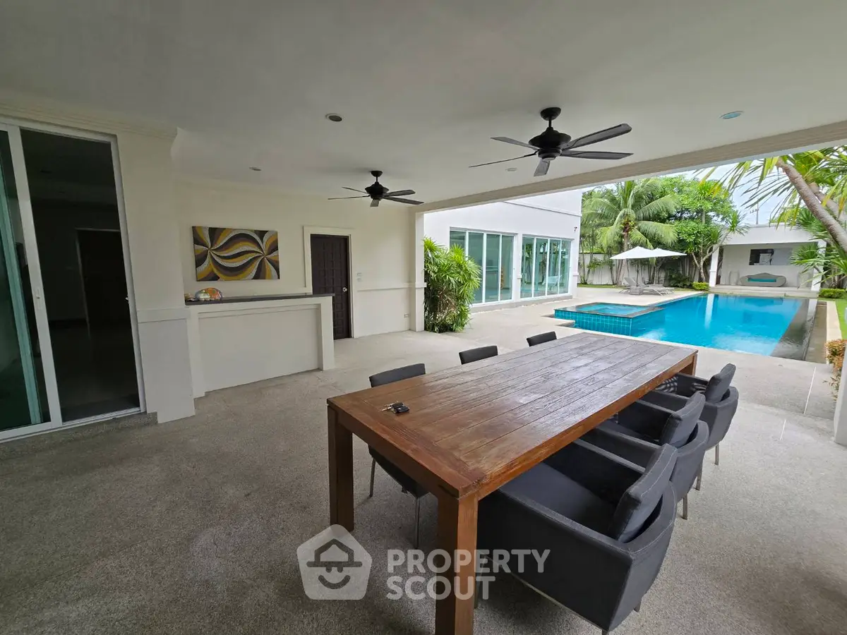 Luxurious outdoor patio with dining area and pool view in modern villa
