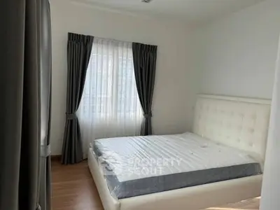 Spacious bedroom with elegant curtains and modern bed frame, perfect for relaxation.