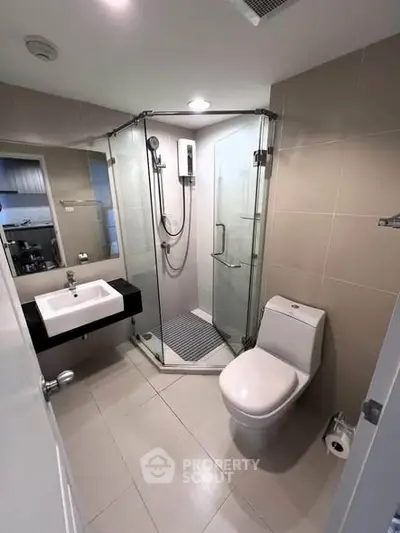 Modern bathroom with glass shower enclosure and sleek fixtures in a contemporary apartment.