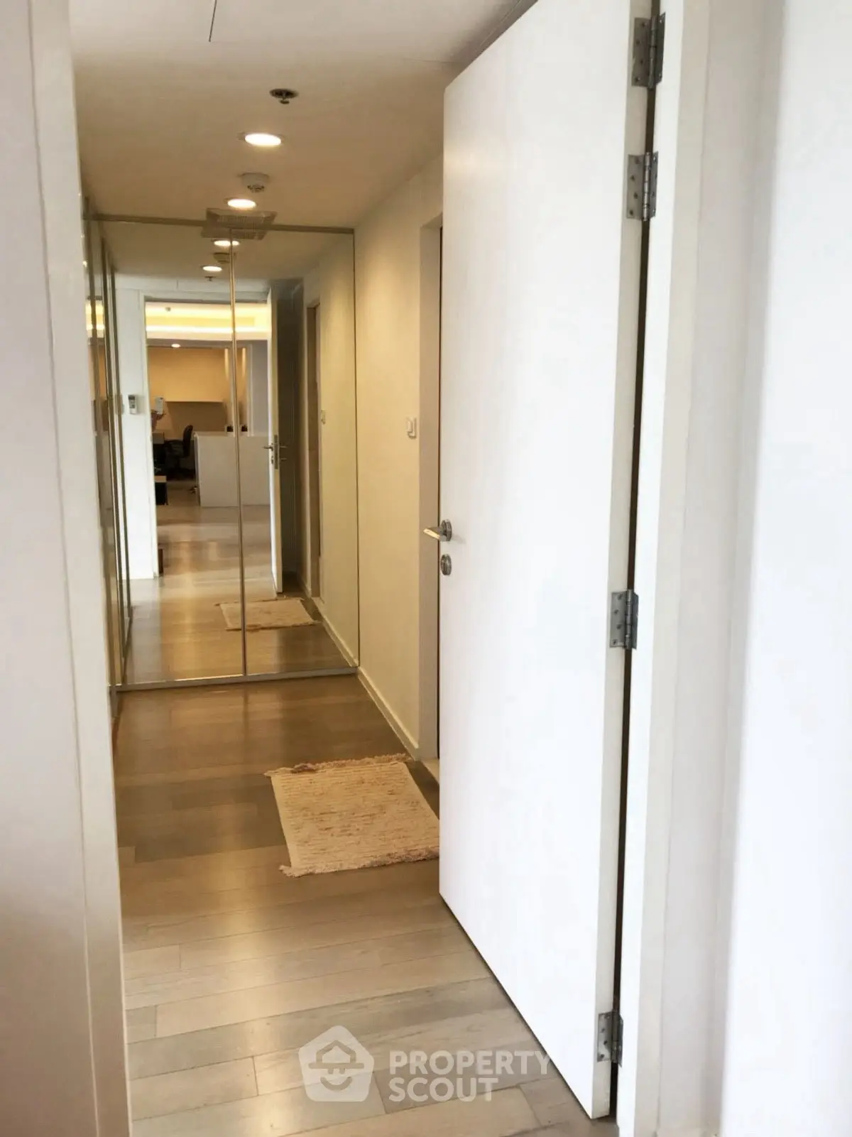 Modern apartment hallway with wooden flooring and mirrored closet doors